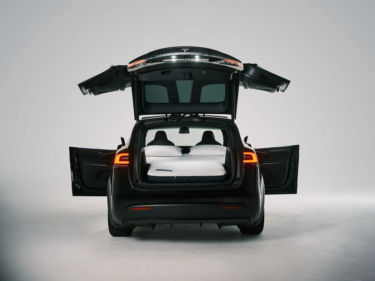Tesla Model X with its hatch and Falcon Wing doors open around an installed two-pillow Snuuzu bed