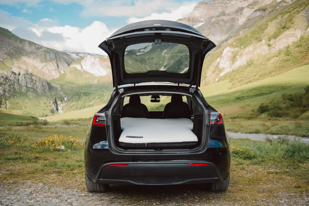 Snuuzu mattress installed in a Tesla Model Y with the rear hatch open at a mountain campsite