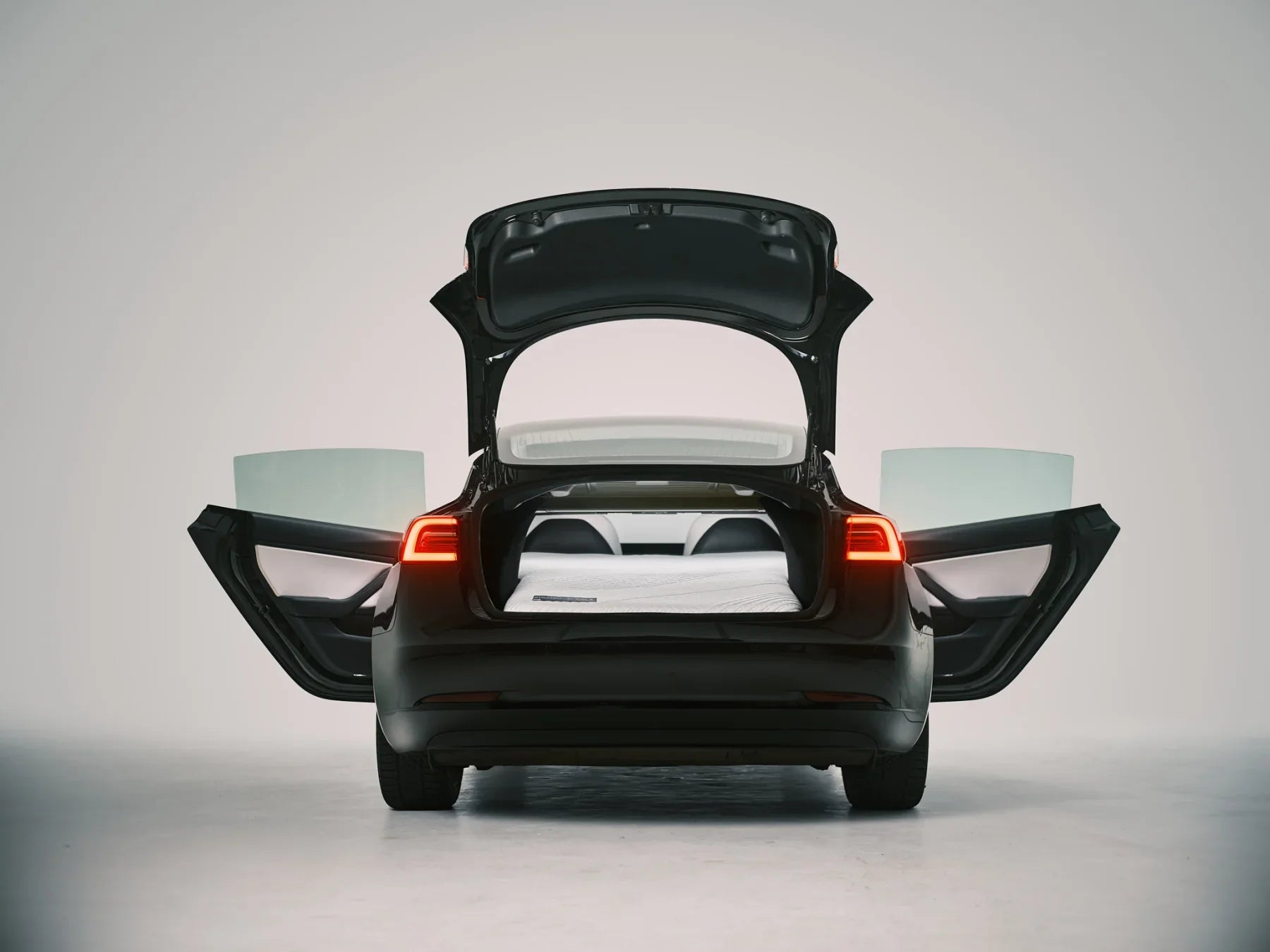 Tesla Model 3 with its trunk and rear doors open around an installed Snuuzu mattress
