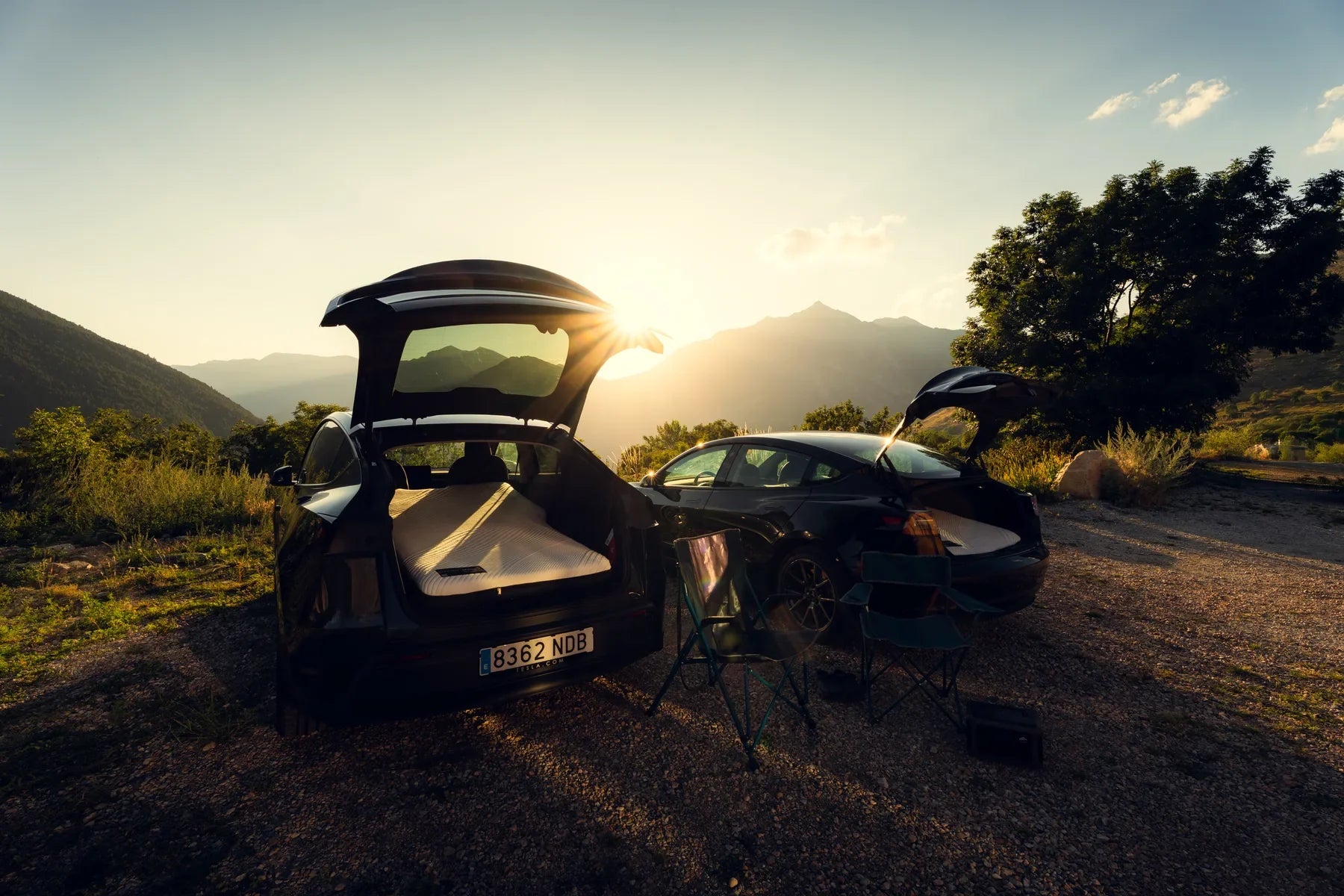 Two Tesla Model Y cars with Snuuzu mattresses at a mountain campsite
