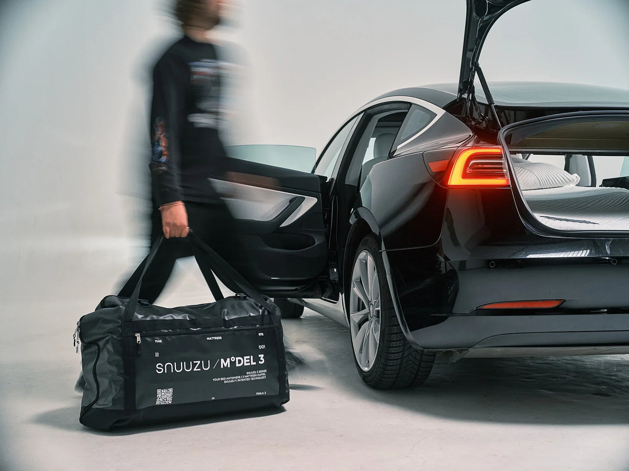 Snuuzu Model 3 mattress bag beside a Tesla Model 3 with the bed installed
