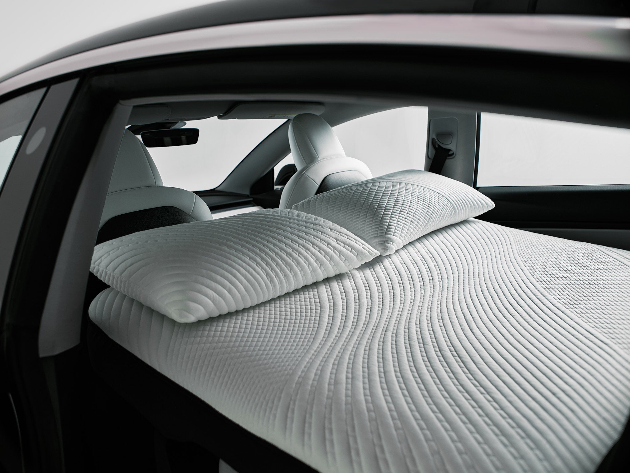 Snuuzu Tesla Model 3 car camping mattress installed inside the vehicle showing full interior sleeping setup with pillows